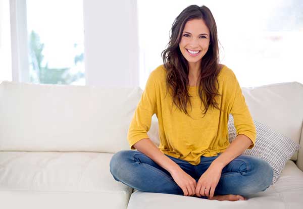 A woman with bright white smile sitting on sofa