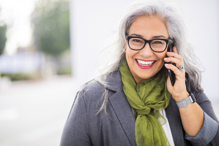 A smiling patient contacting Surf City Oral and Maxillofacial Surgery on a cell phone.