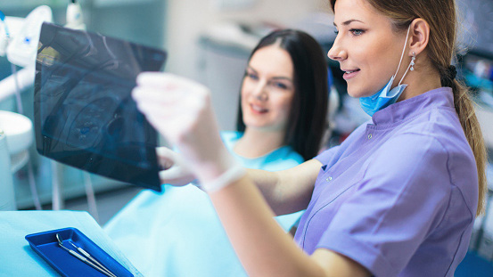 Female dentist showing x-ray image to patient.