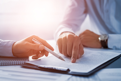 Dentist and patient point at paperwork and forms on a clipboard