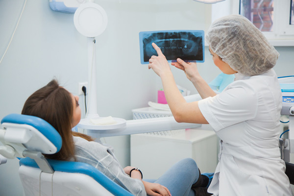 Dentist showing patient X-rays before bone grafting surgery at Surf City Oral and Maxillofacial Surgery in Huntington Beach, CA