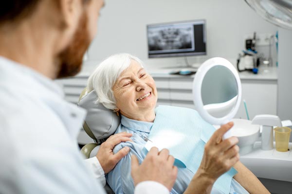 Elderly woman enjoying her new smile with implant supported dentures at Surf City Oral and Maxillofacial Surgery in Huntington Beach, CA