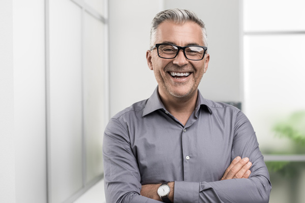 Man smiling with his arms crossed after receiving ridge augmentation at Surf City Oral and Maxillofacial Surgery in Huntington Beach, CA