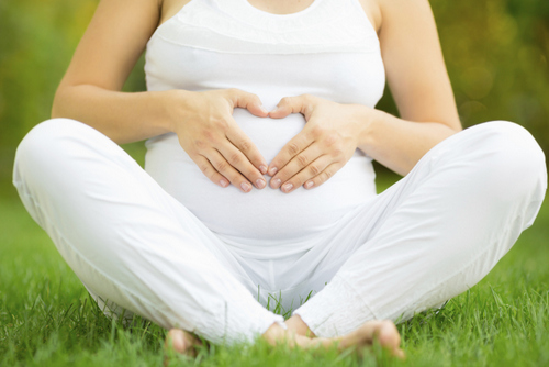 A pregnant woman sitting on grass